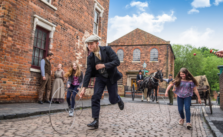 Children in Victorian costume play with a hoop at the Black Country Living Museum