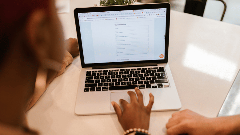A person uses a laptop to fill out an online form