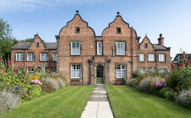 Traditional building with green lawn and flower borders.