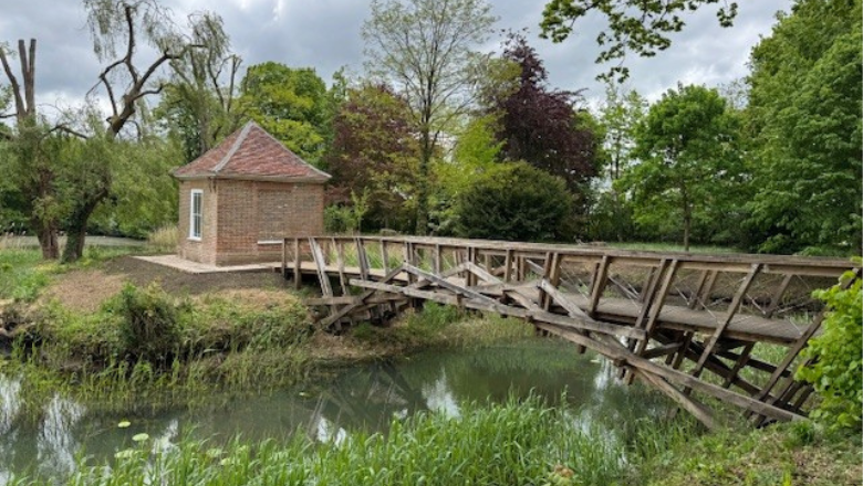 A wooden bridge across a river to a building on the other side.