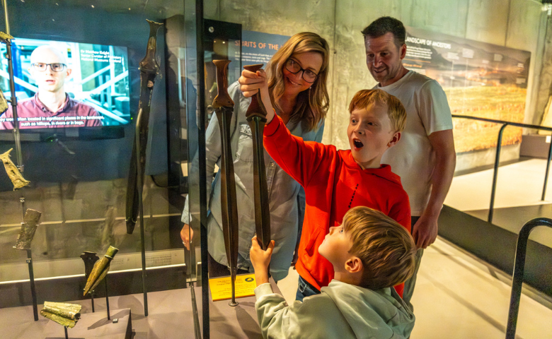 Kilmartin Museum, credit Aaron Watson A family look excitedly at a sword exhibit in a museum gallery