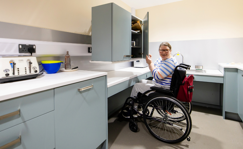 Paul's Place - credit Rebecca Faith A woman in a wheelchair opens a cupboard in a specially designed accessible kitchen
