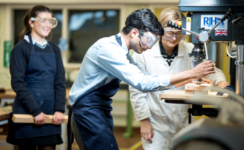 St Benedict's College A student wearing safety goggles uses machinery in a DT classroom